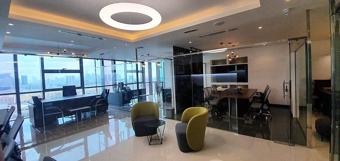 Office floor with glazed partitions, linear lighting and neutral finishes