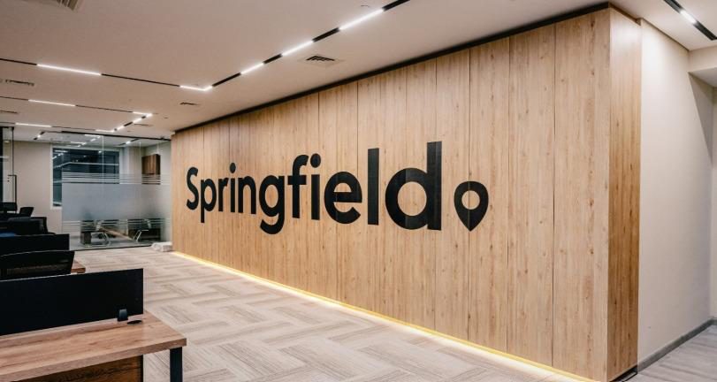 Springfield office reception with a backlit timber feature wall carrying the company name