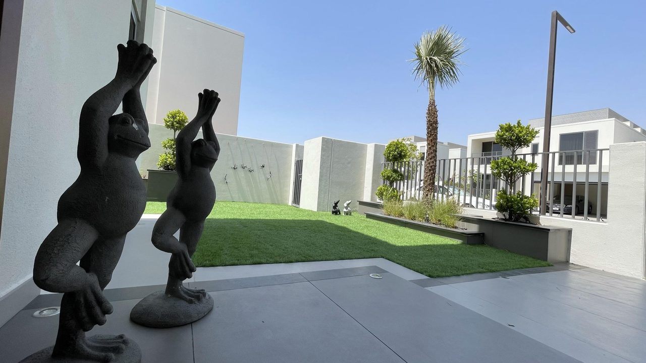 Finished villa garden with sculpture, lawn and mature planting