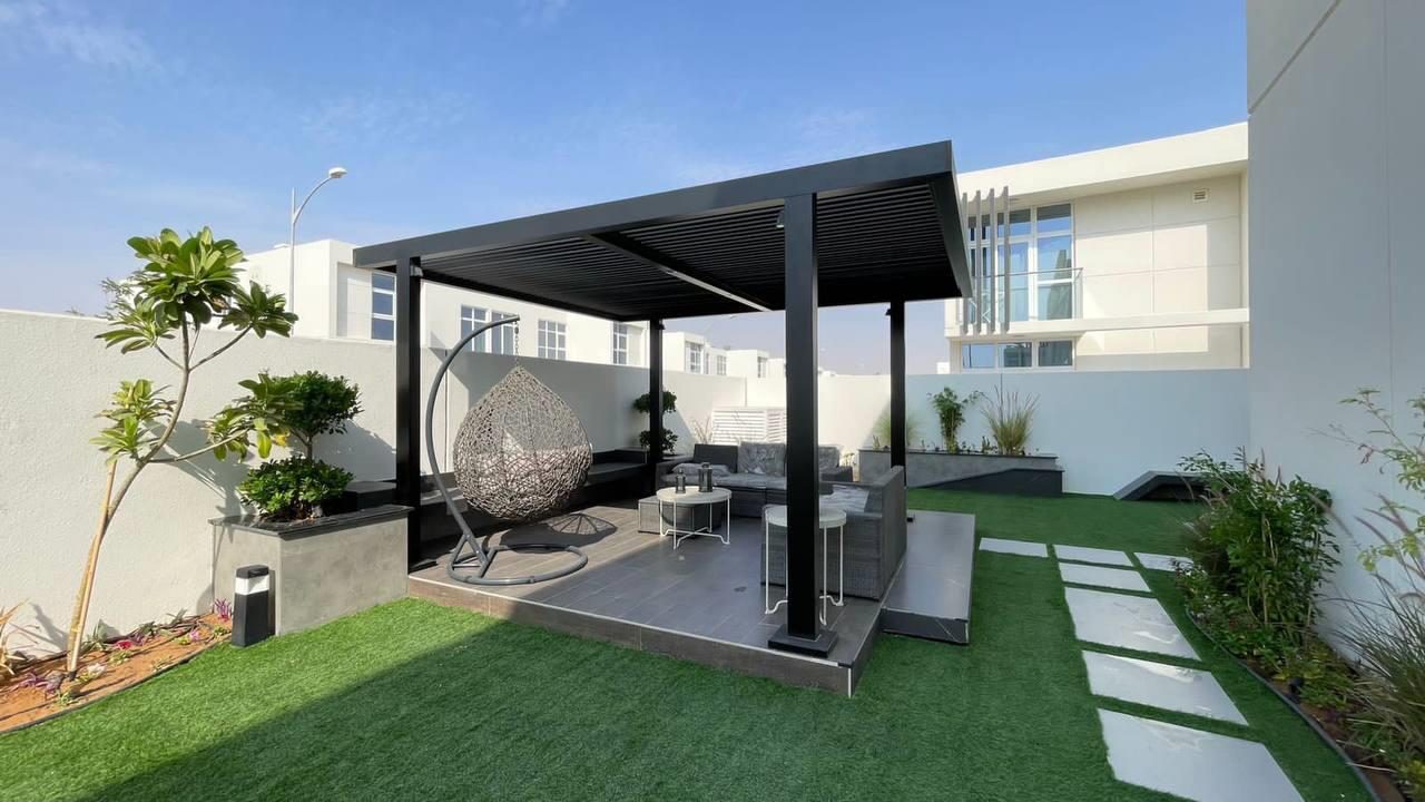 Villa garden with a pergola over an outdoor dining terrace beside a lawn