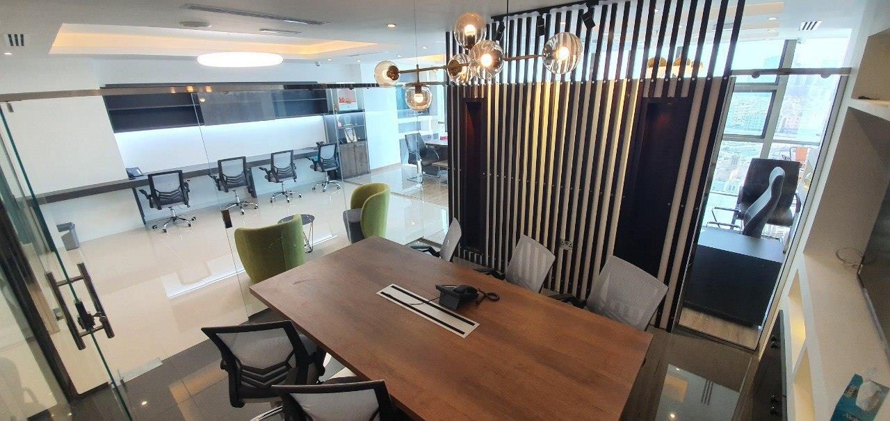 Meeting room with a solid timber table, slatted acoustic wall and linear lighting